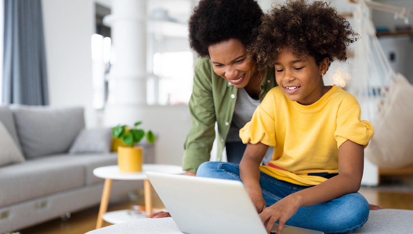 African American mother and daughter using laptop at home.