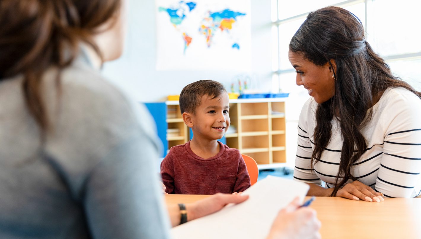 A child psychologist talks with a boy and his mom during a play therapy appointment.